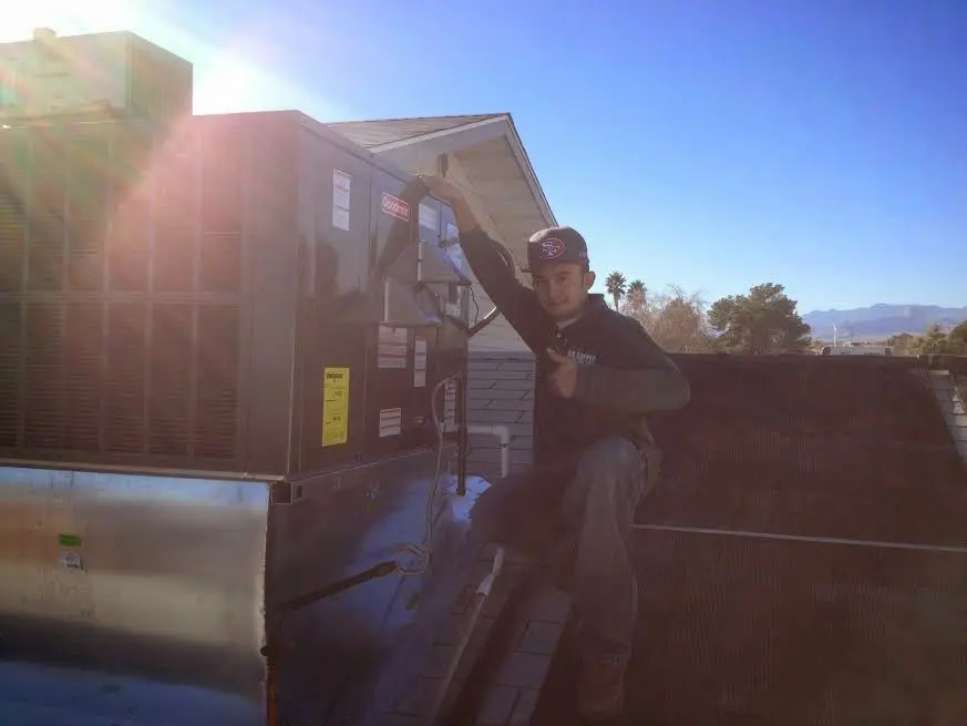 HVAC technician performing AC Tune-Up on a rooftop unit in Horizon City