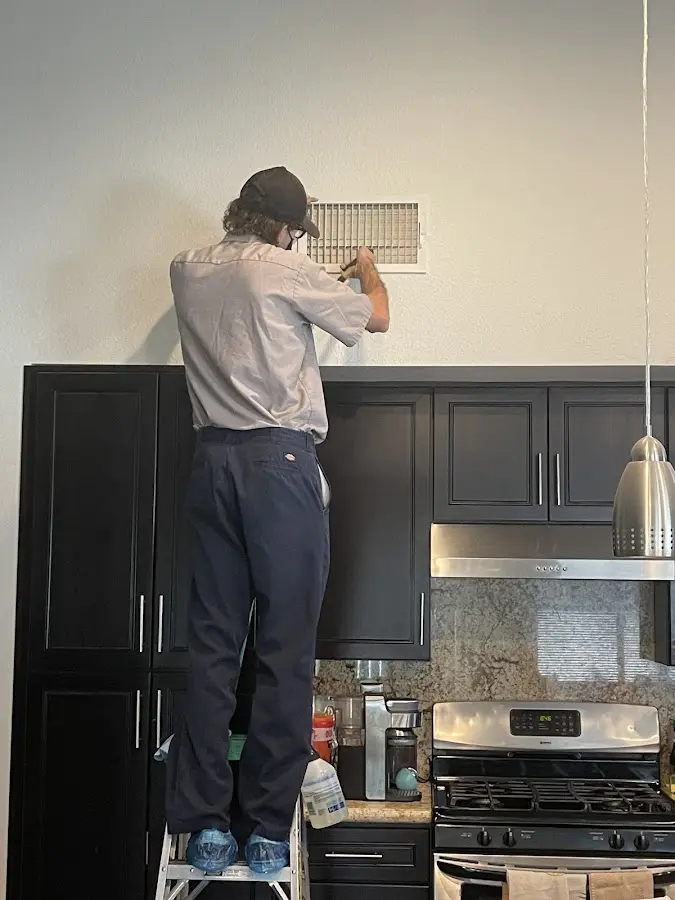 Technician inspecting an air vent during HVAC service in Horizon City